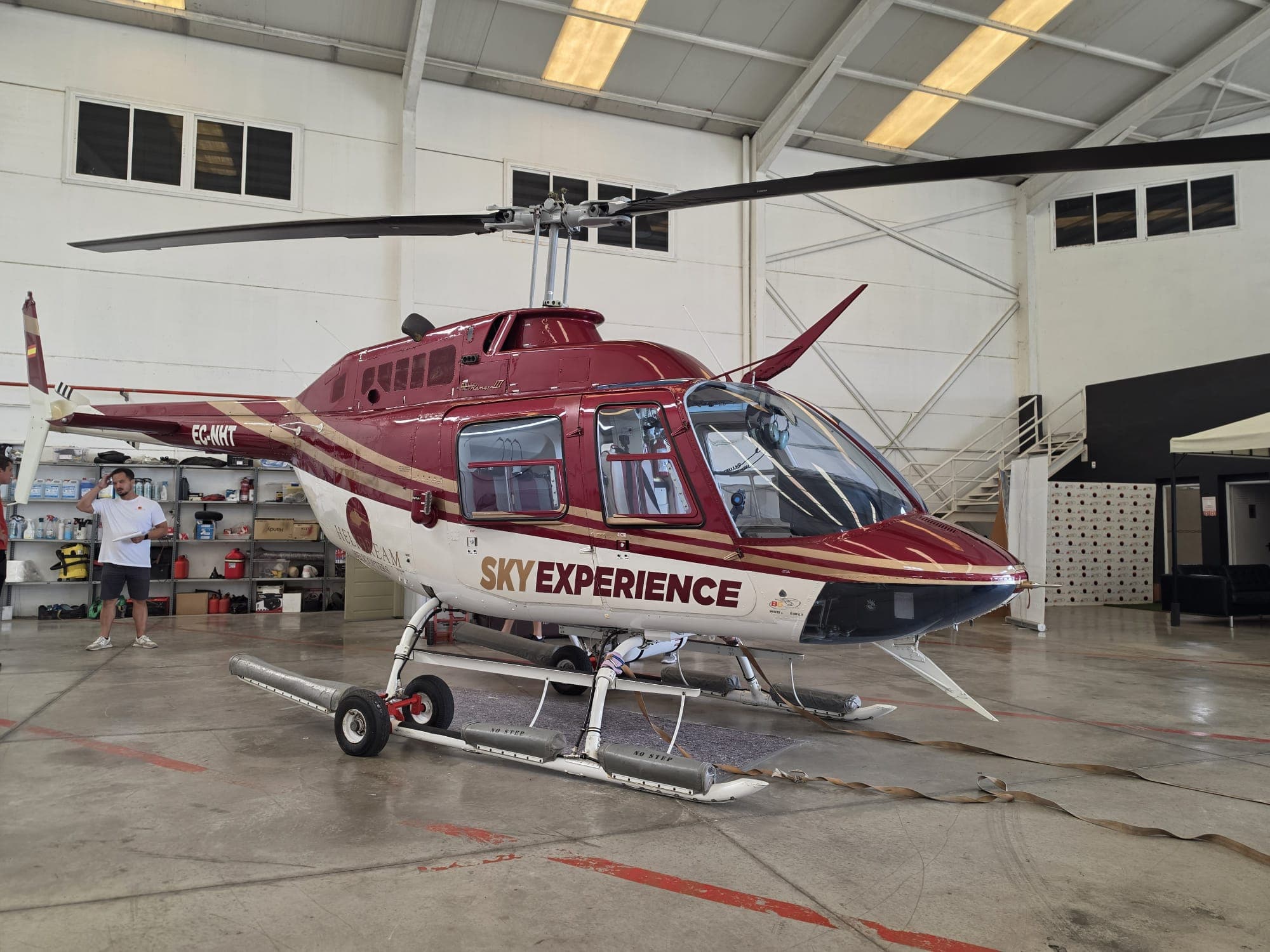 Helicóptero Bell 206 con la rotulación Sky Experience en granate, dorado y blanco