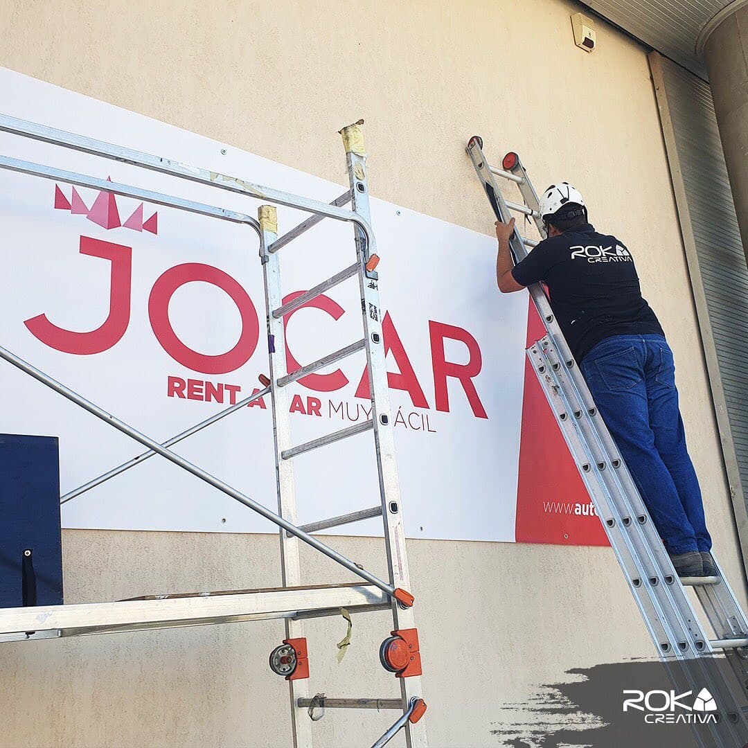 Instalador de Roka Creativa fijando la lona de Jocar en la fachada