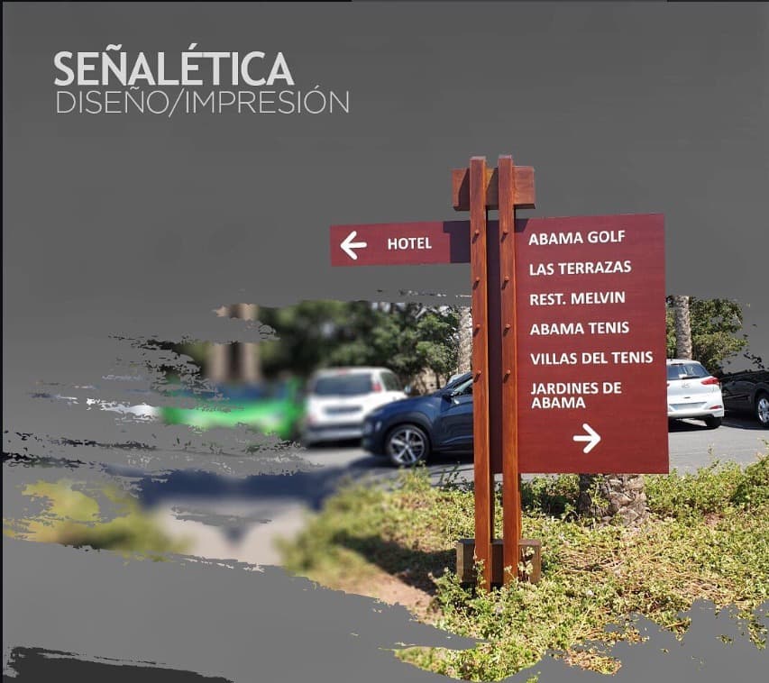 Señalética direccional exterior sobre postes de madera en el resort Abama